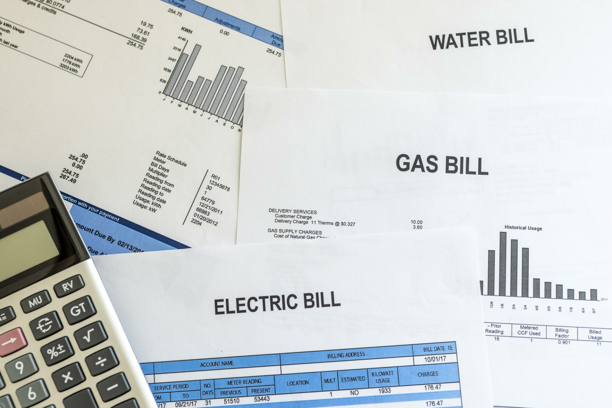 Electricity and water utility bills on table with calculator